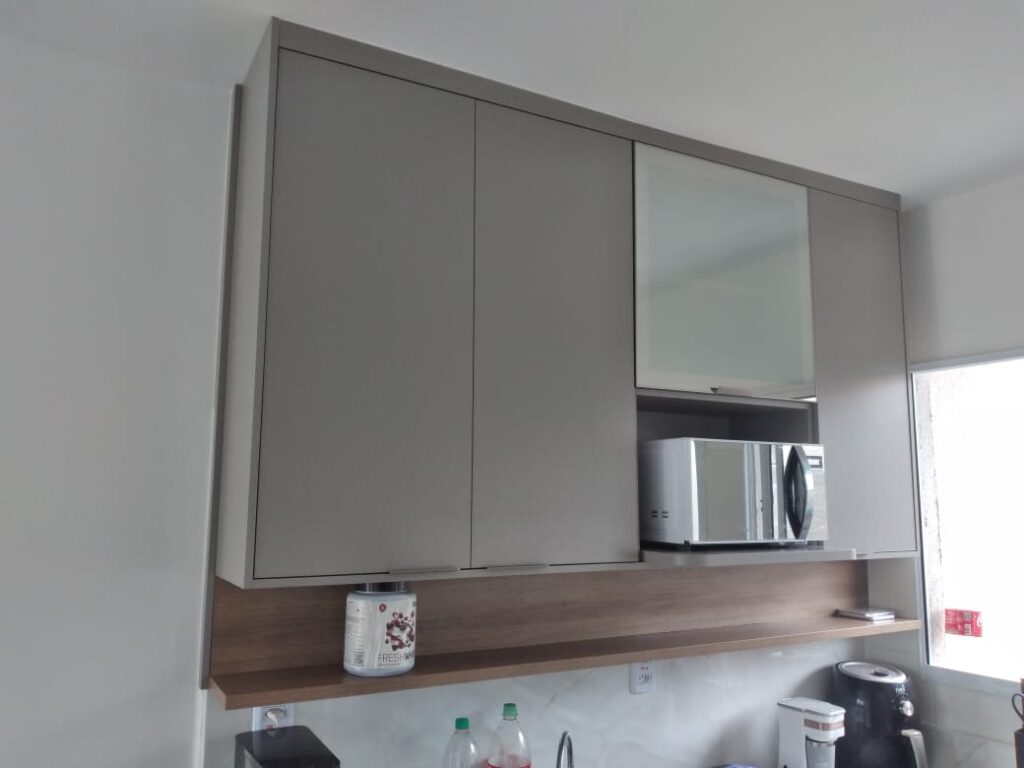 Cozinha planejada com bancada em L e armários amadeirados, projeto Kless